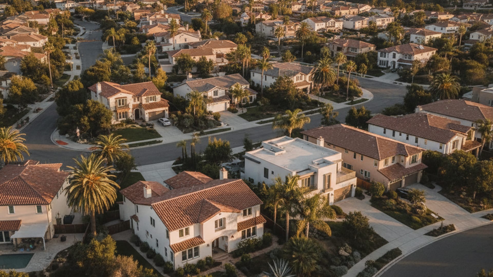 Aerial view of a San Diego County residential neighborhood with stucco homes and outdoor AC units visible in side yards at golden hour